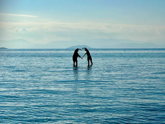 Two travelers forming a heart with their arms in the calm sea