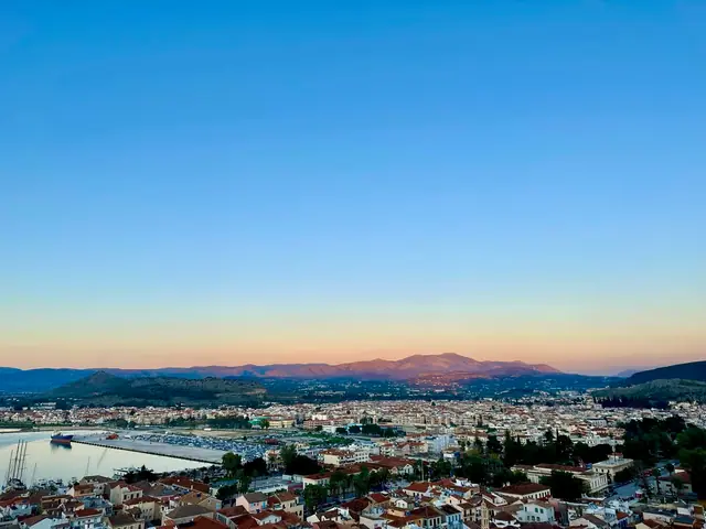 A hilltop panorama over a Greek coastal town at dusk