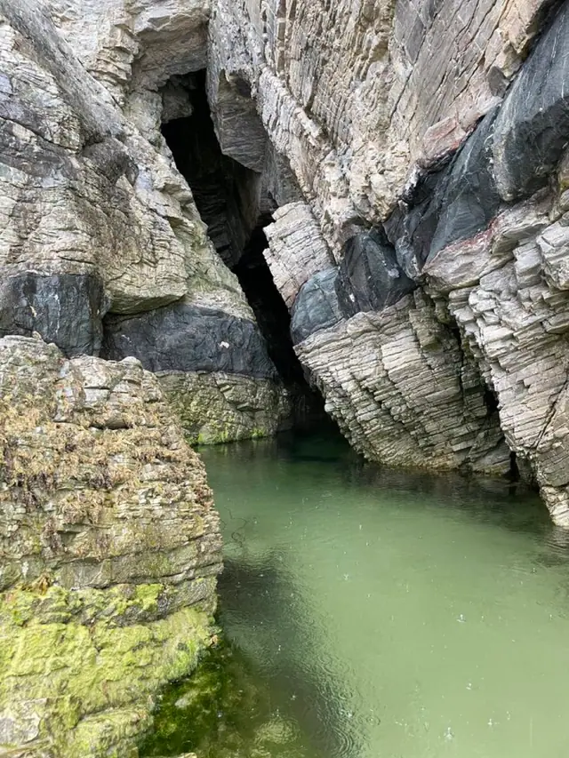 Turquoise water in a hidden sea cave between striated rock walls