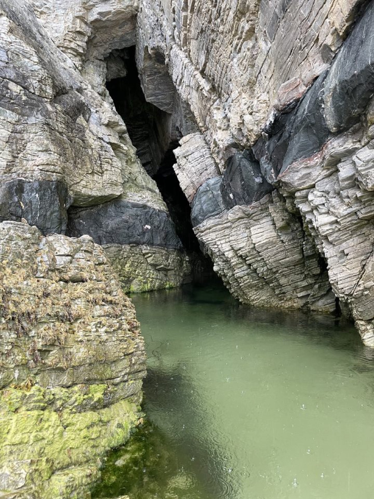 Turquoise water in a hidden sea cave between striated rock walls