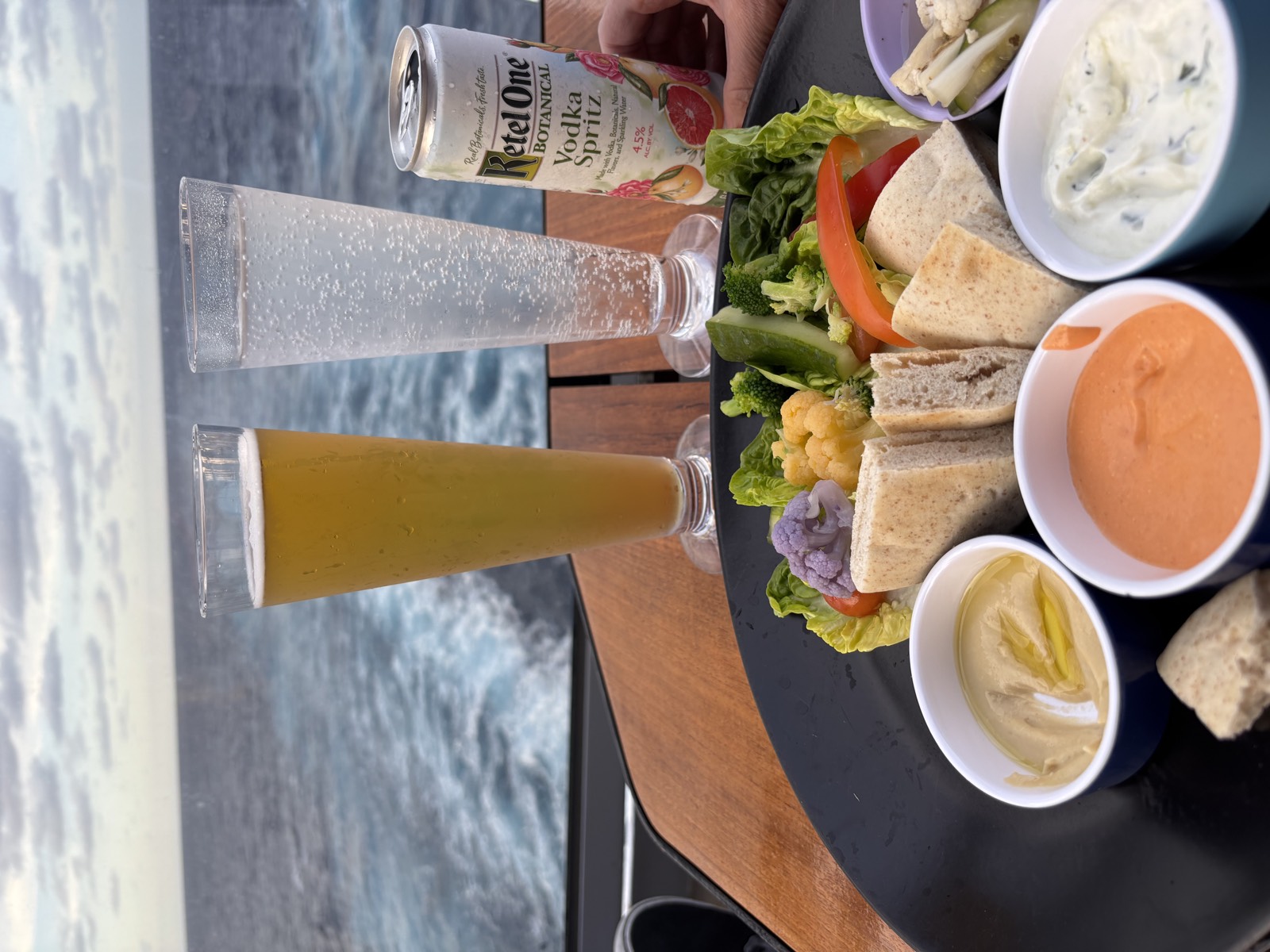 A lunch platter and drinks on a boat with the ocean wake trailing behind