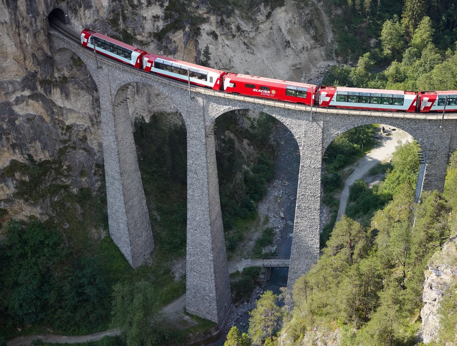 The Glacier Express crossing the Landwasser Viaduct in Switzerland, a famous stone bridge that spans the Landwasser River valley.