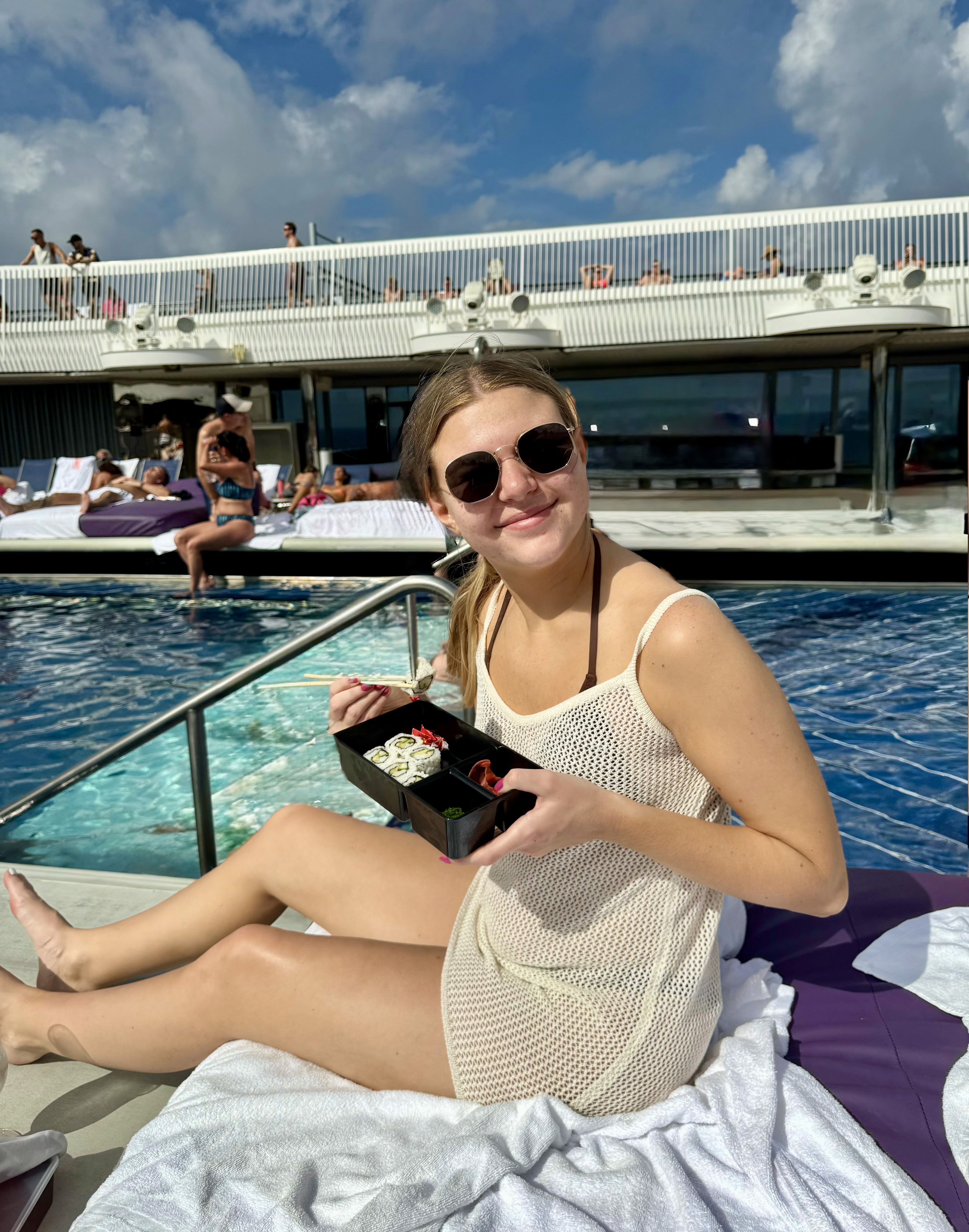 A traveler enjoying lunch beside a cruise ship pool on a sunny sea day